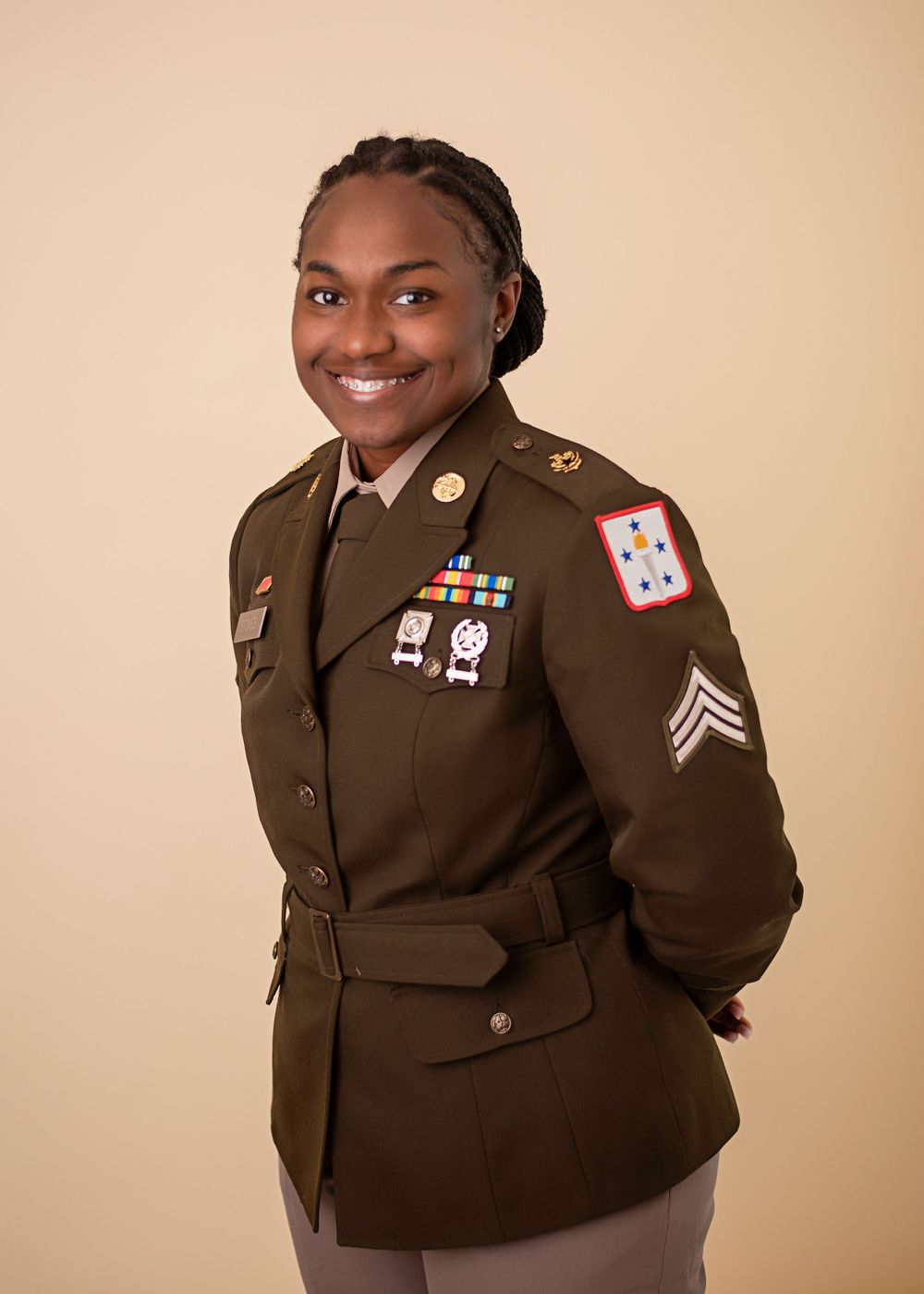Military service member in dress uniform with medals and decorations poses for portrait.