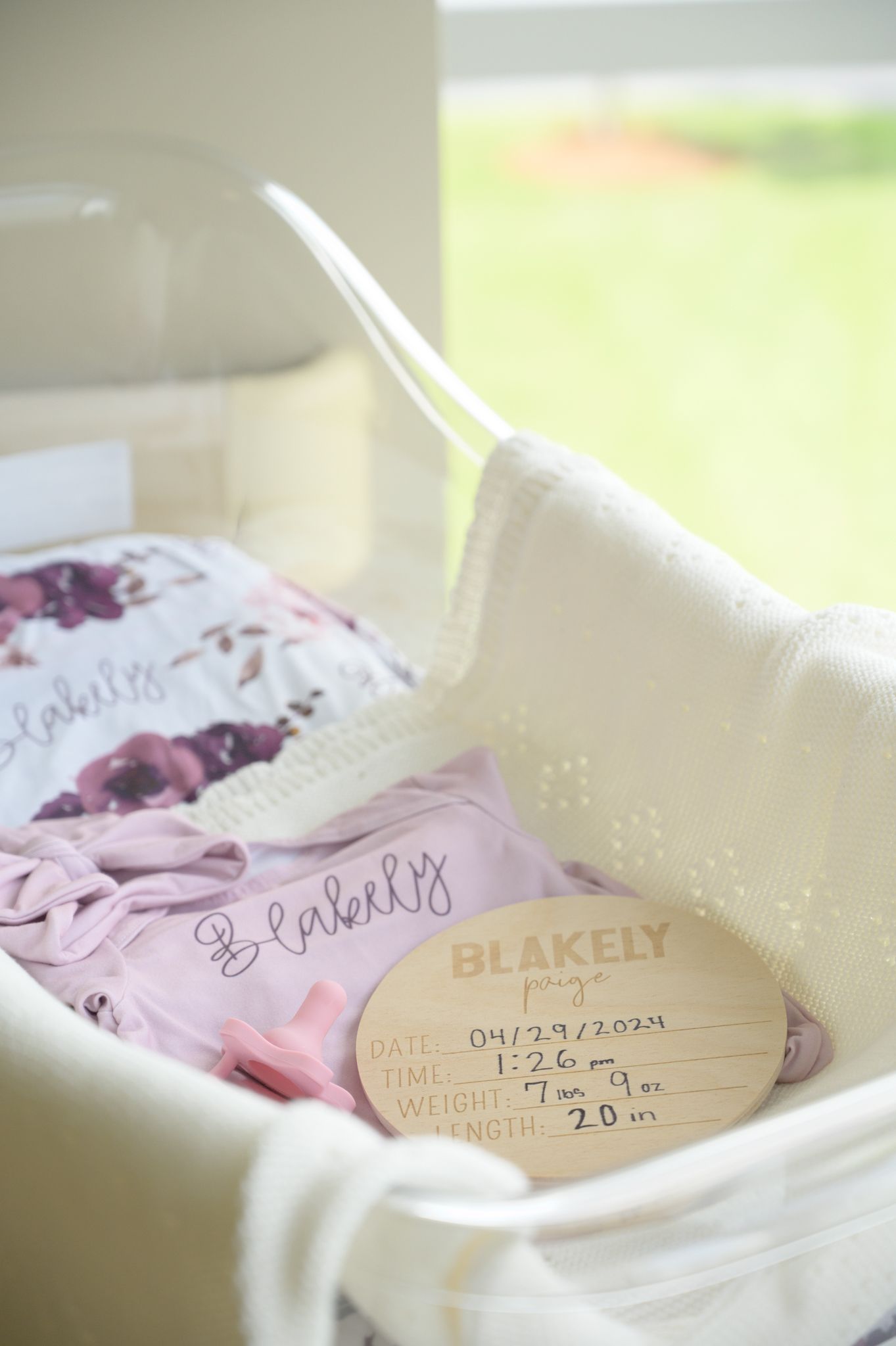 Baby keepsake display showing wooden birth announcement disc and pink accessories.