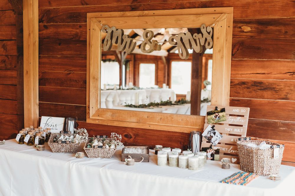 Rustic wedding reception decor featuring wooden mirror frame and white tablecloth with decorative elements.