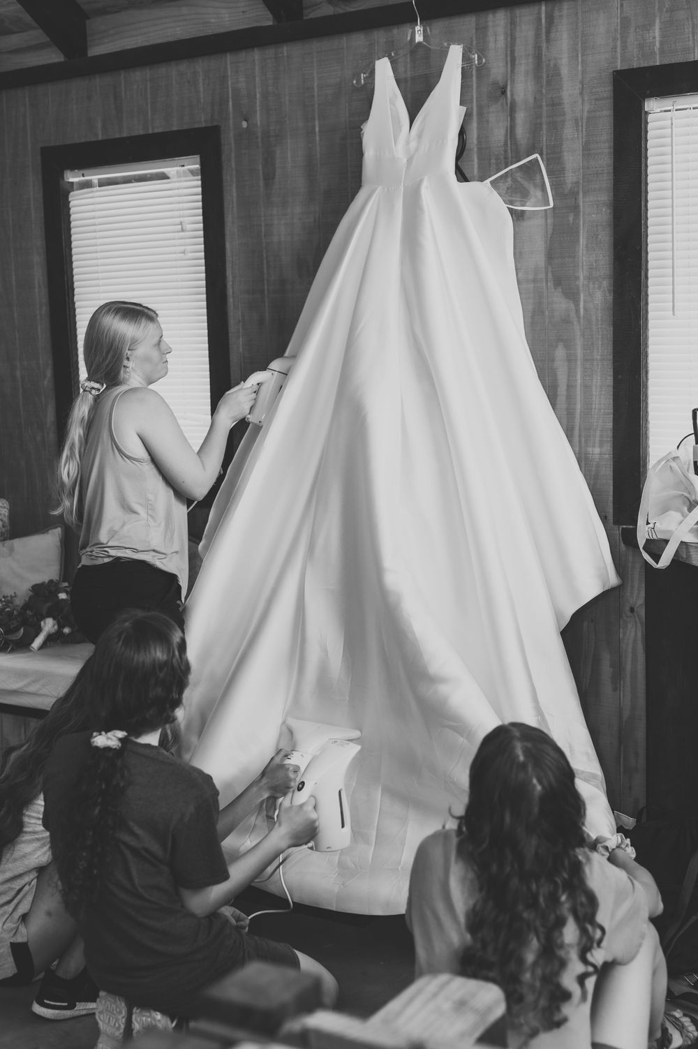 Wedding dress preparation scene showing white ballgown being steamed and adjusted.