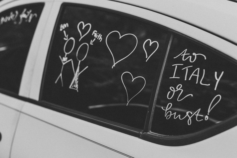 Romantic doodles and hearts drawn on a car window with 'Italy' written in chalk.