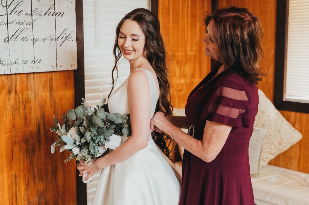 Wedding preparation scene with bridal gown and bouquet against wooden wall.