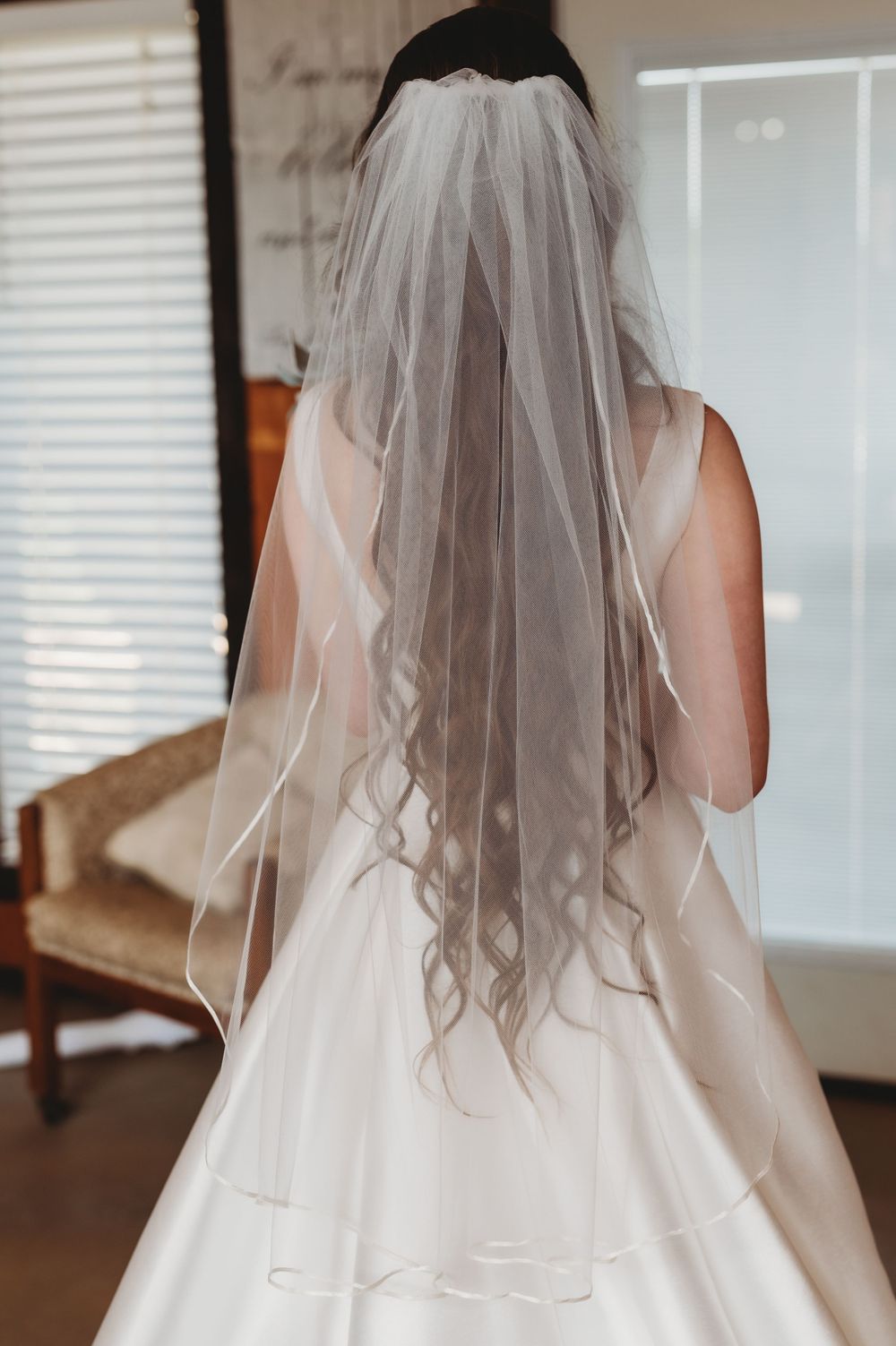 Back view of bride wearing a flowing veil with long wavy hair.