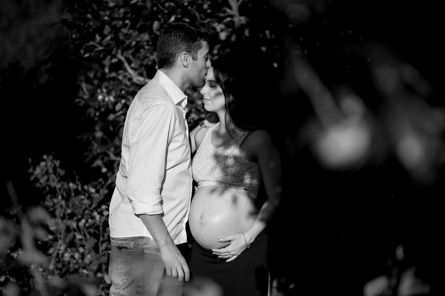 An intimate black and white maternity portrait captured outdoors at dusk.