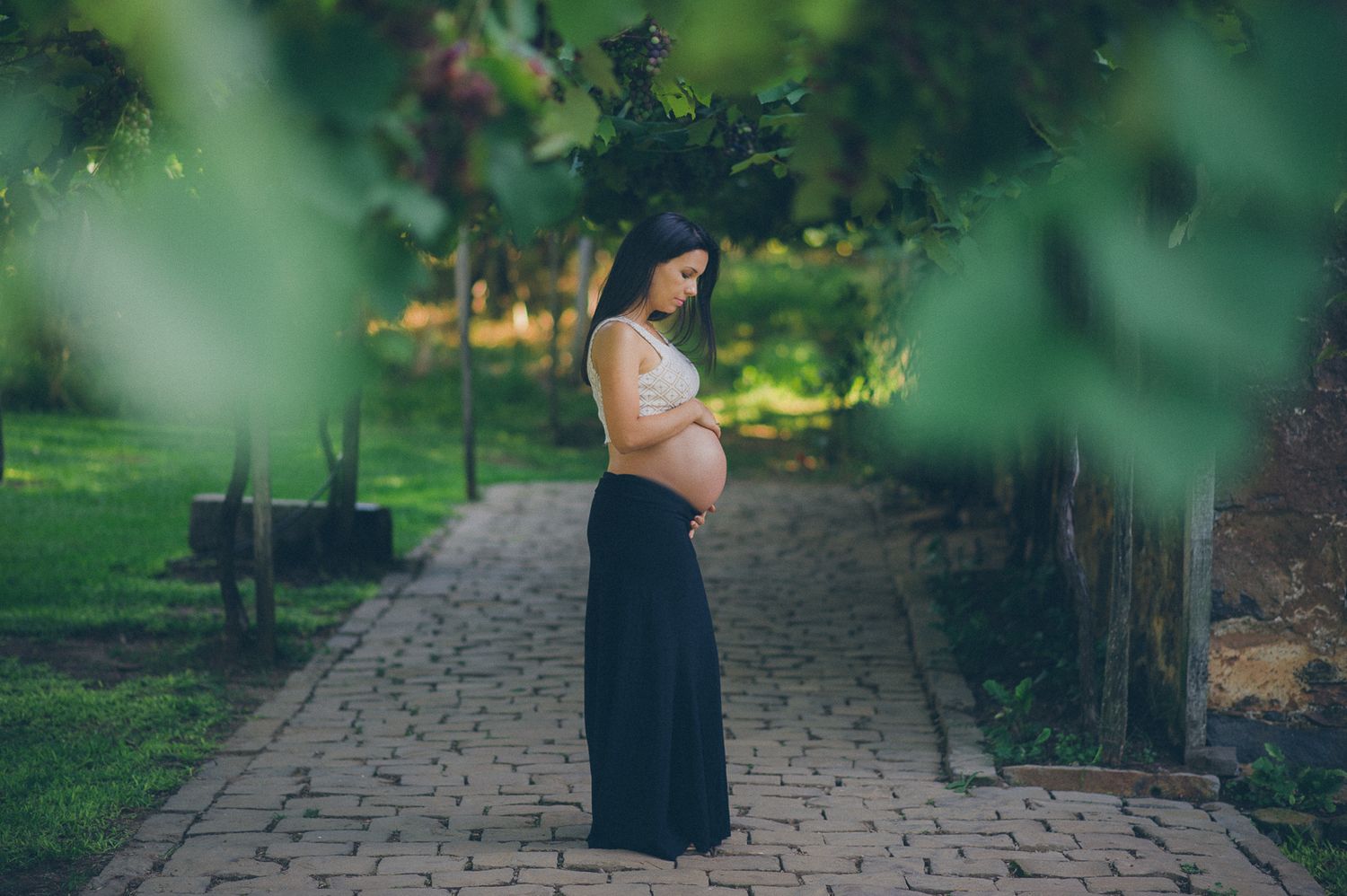 A serene maternity portrait on a stone path surrounded by greenery.
