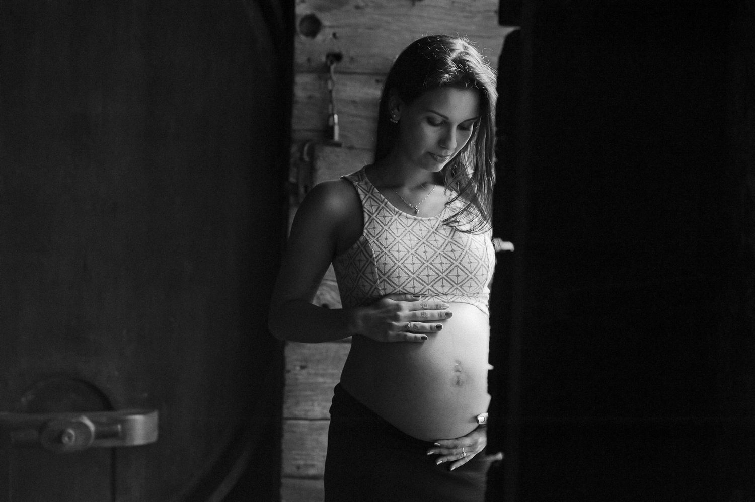 A dramatic black and white maternity portrait in soft window light.