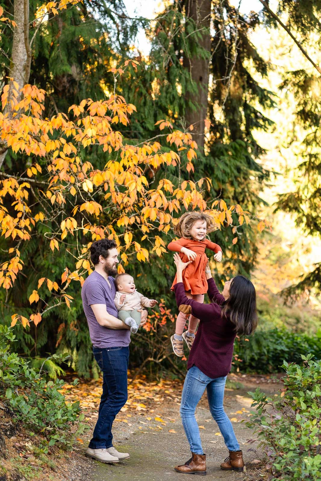 Mother throws her daughter into the air in a Seattle park.