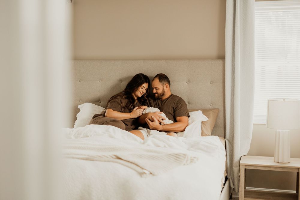 An intimate family moment captured while resting together in bed.