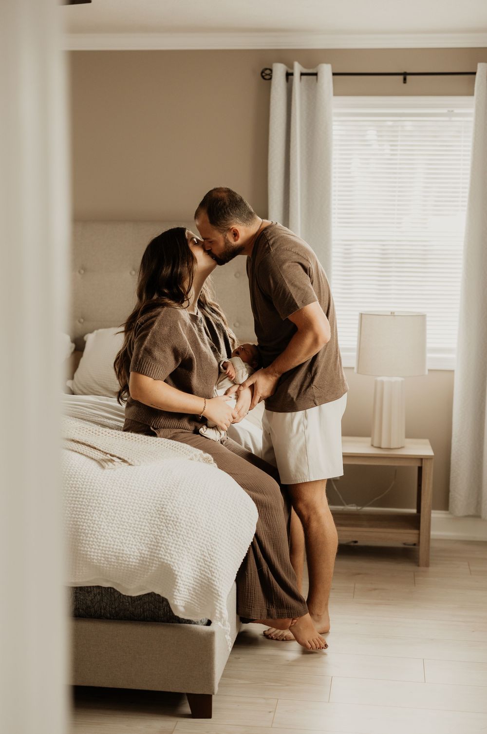 A couple shares a tender moment while sitting on their bed.