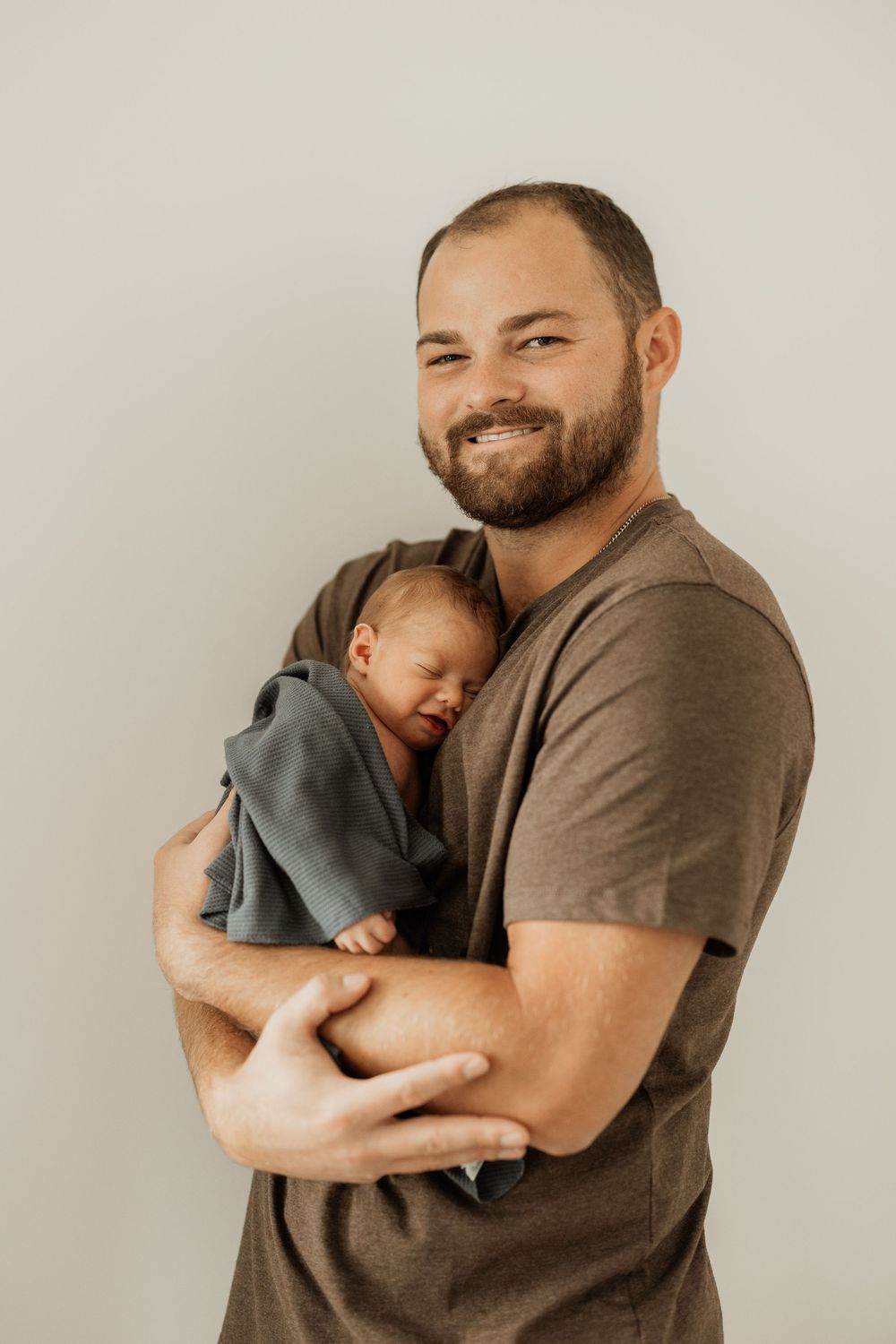 Heartwarming portrait of a parent holding and embracing a sleeping baby in grey tones.