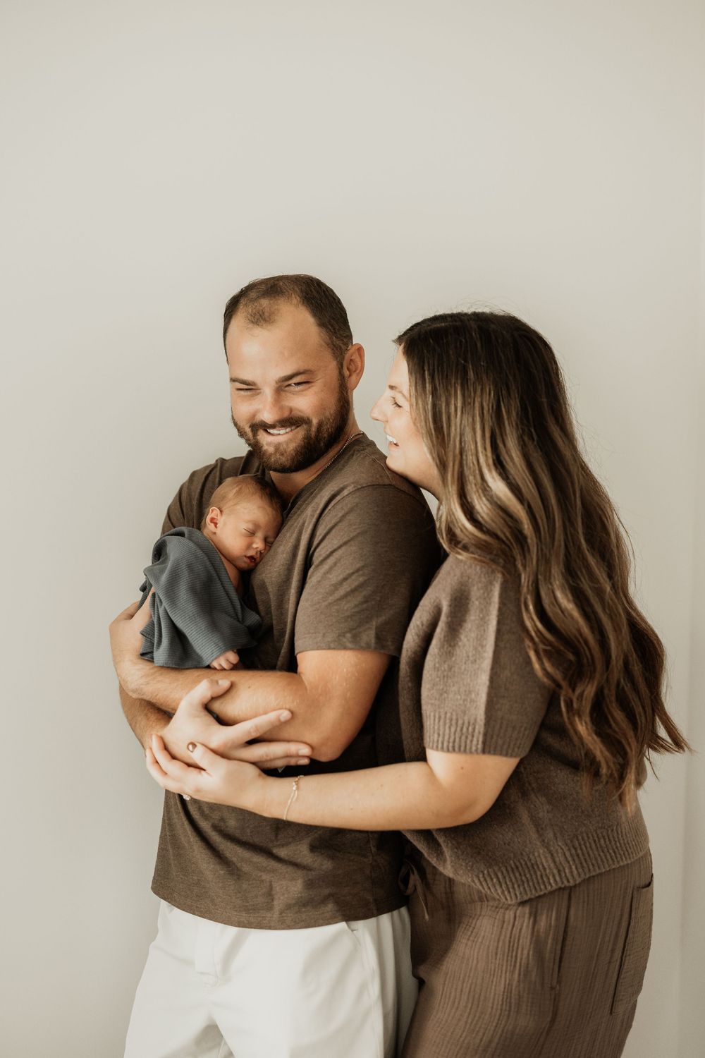 Family portrait showing tender moments of parents cuddling with their newborn baby.