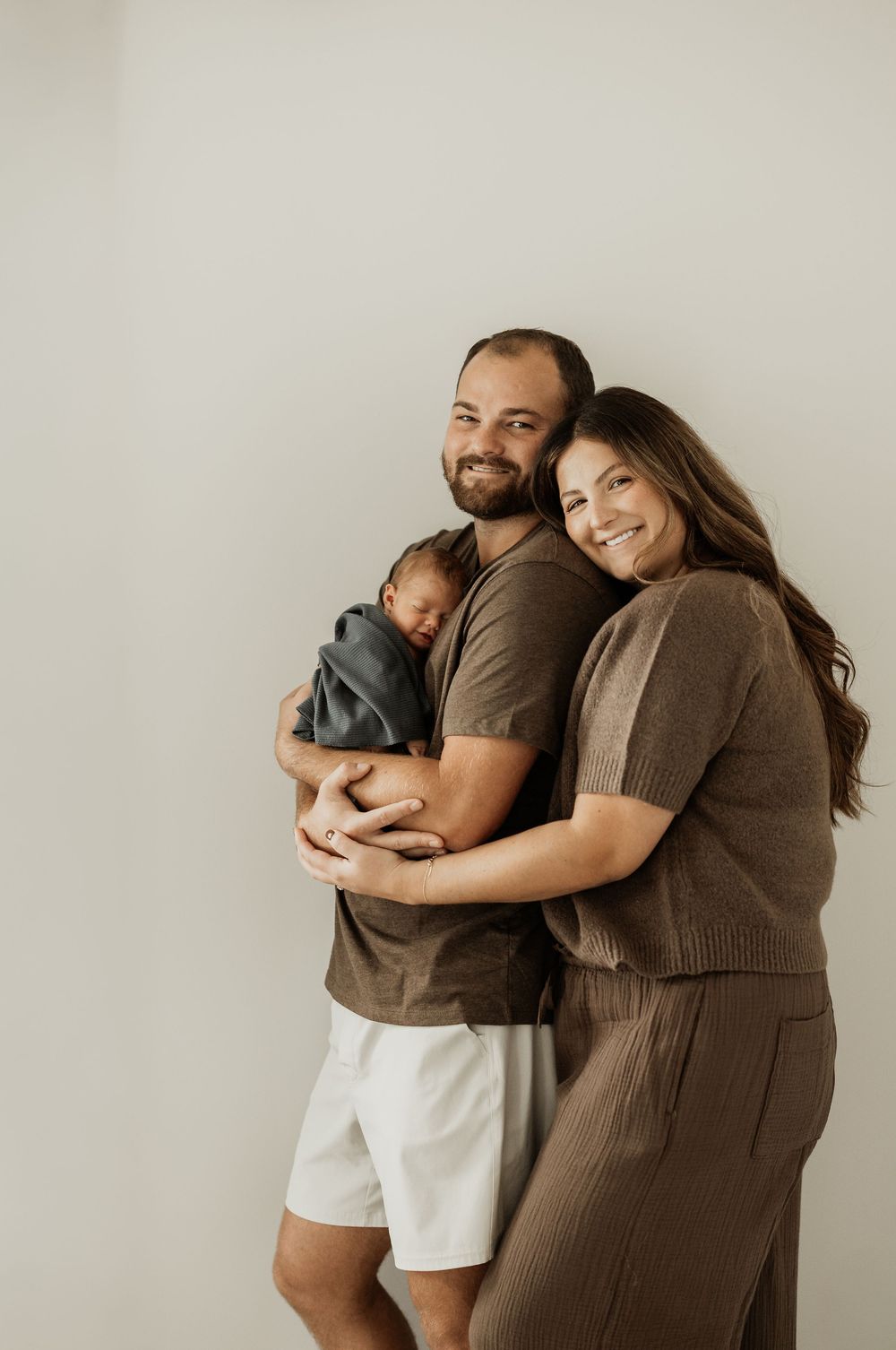 Candid family photo series showing joyful moments with a newborn baby against neutral background.