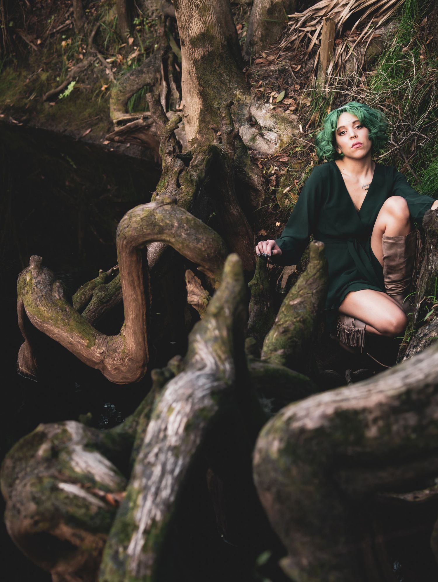 Moody forest photoshoot with dark tree roots and artistic shadows creating mystical atmosphere.