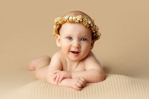 Sweet newborn photography series with floral crown and natural poses on beige background.