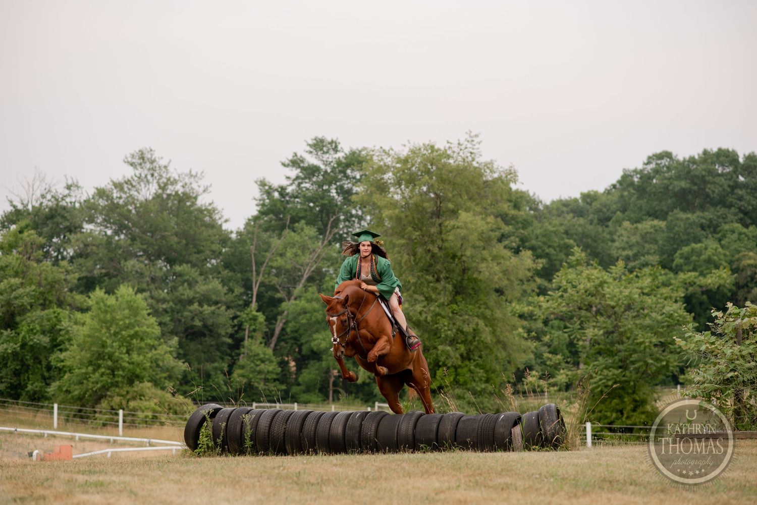 Horse and rider leaping over a row of tires in an equestrian training course.