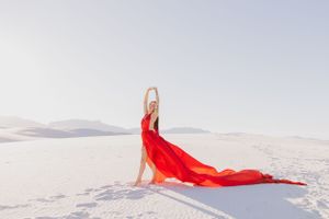 Bright red fabric billowing across pristine white sand dunes.
