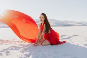 Red fabric creates dynamic motion against pristine white sand in artistic desert photography.