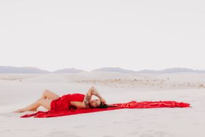 Artistic desert portrait featuring flowing red fabric against pristine white sand dunes.