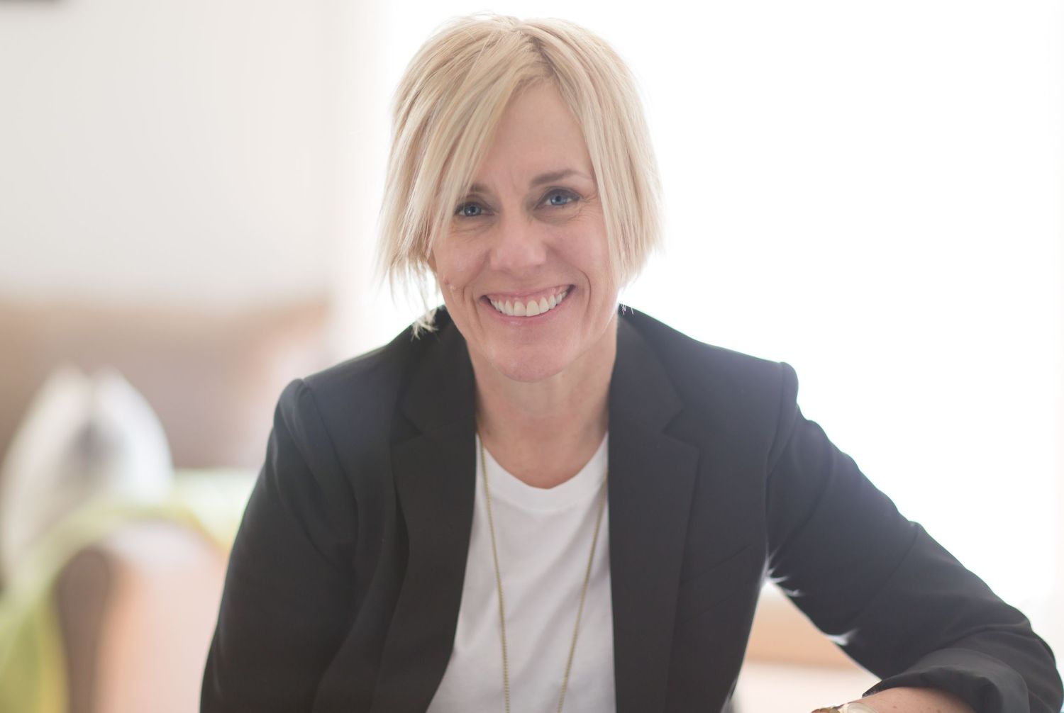 Portrait of therapist and life coach wearing black blazer in office, professional editorial portrait.