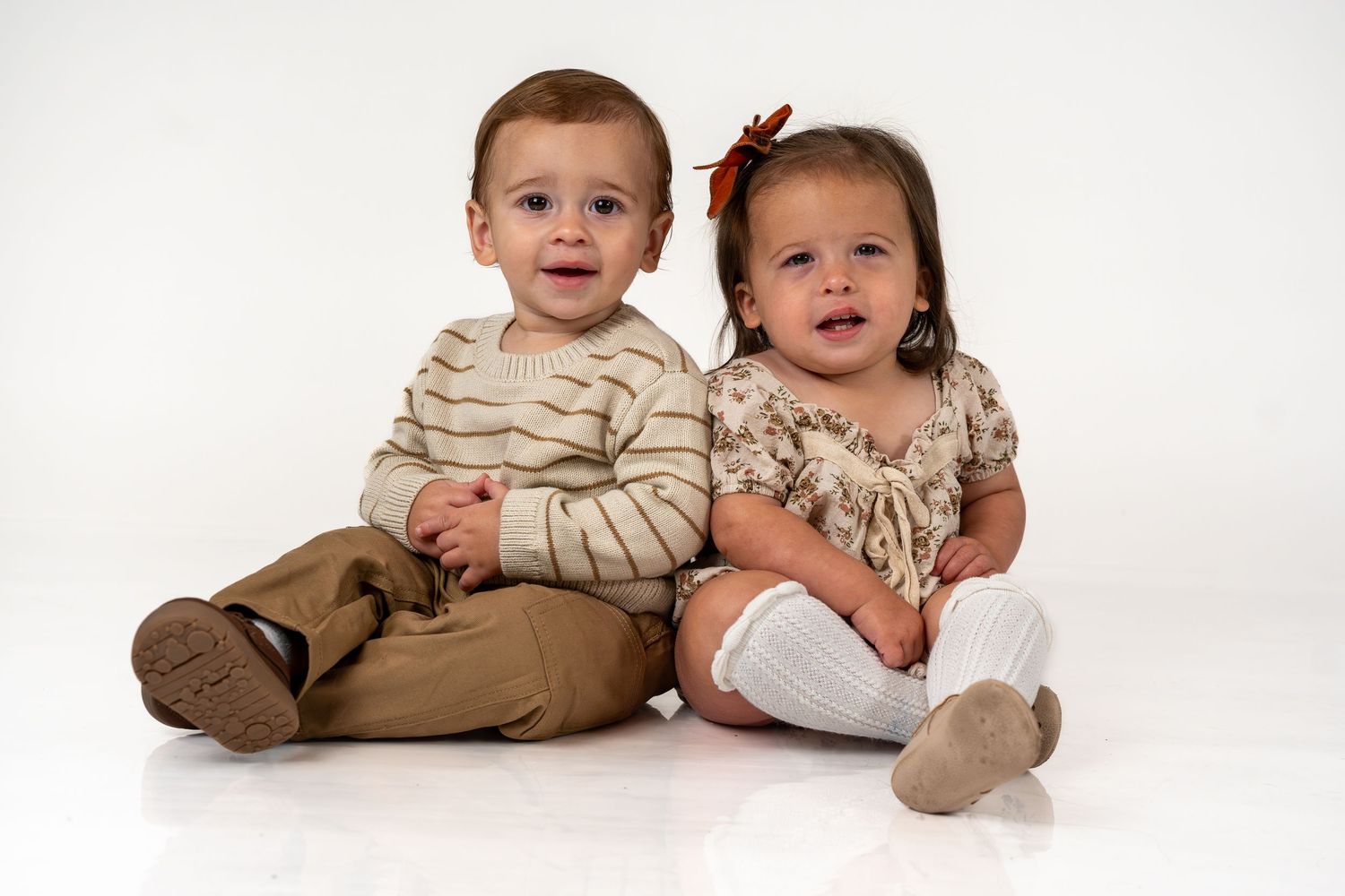 Two small children lying on white background wearing coordinated beige and brown outfits in three different poses.