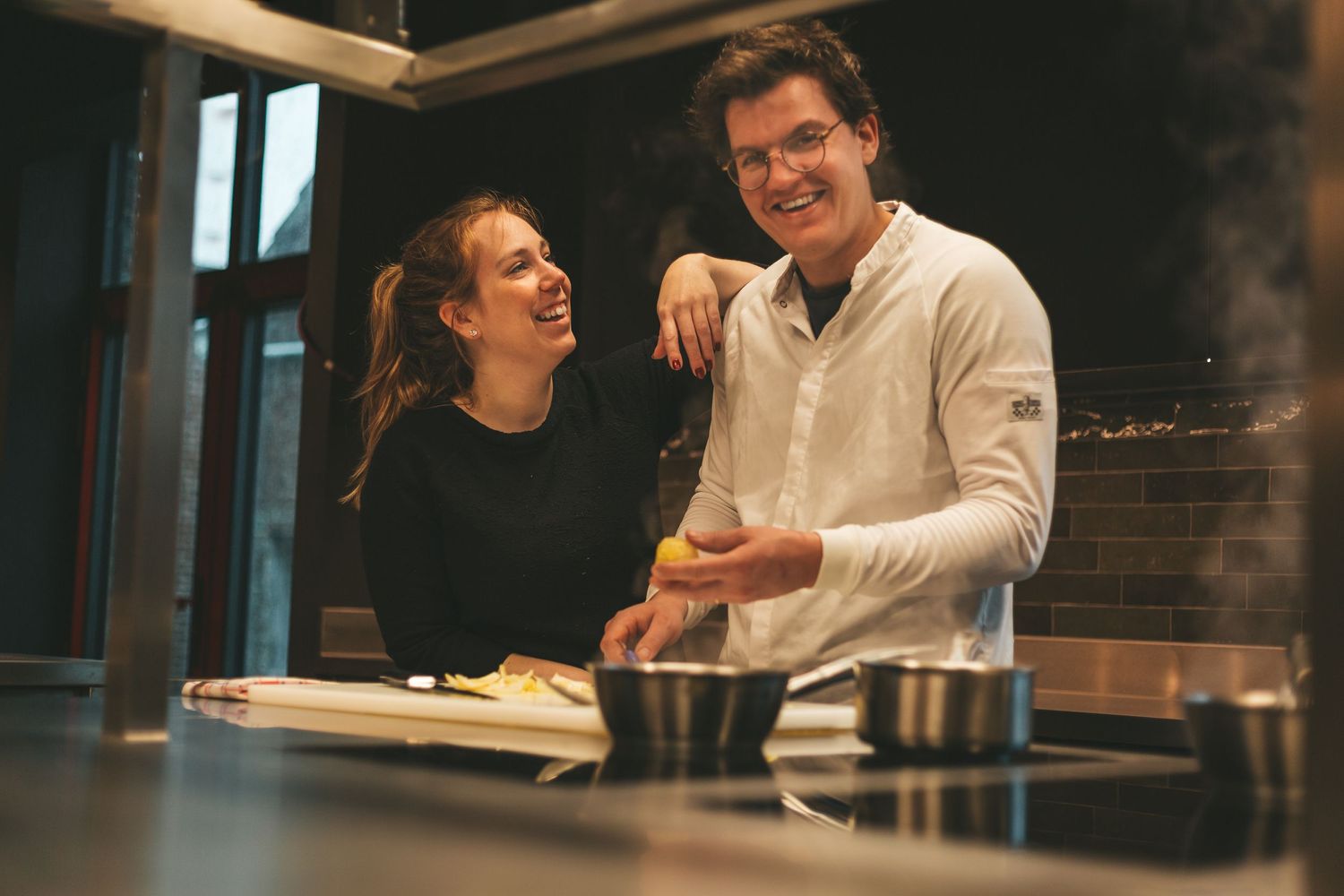 Two people having an animated conversation while sitting at a dining table in a warm, cozy setting.