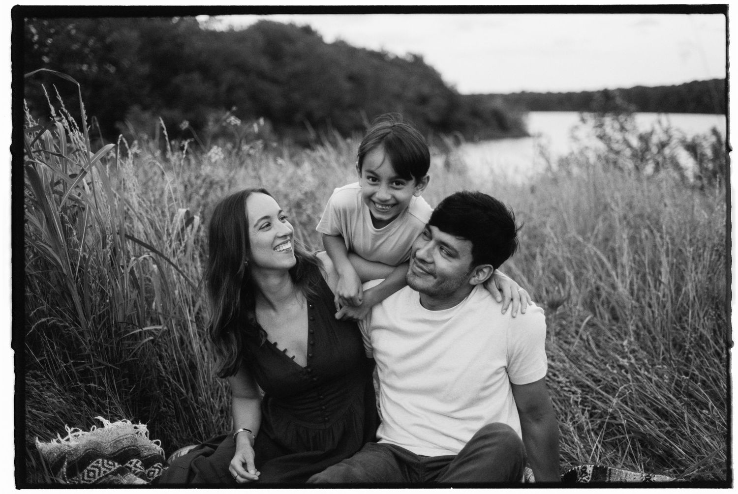 Black and white photo series showing joyful moments between people embracing in a grassy field.
