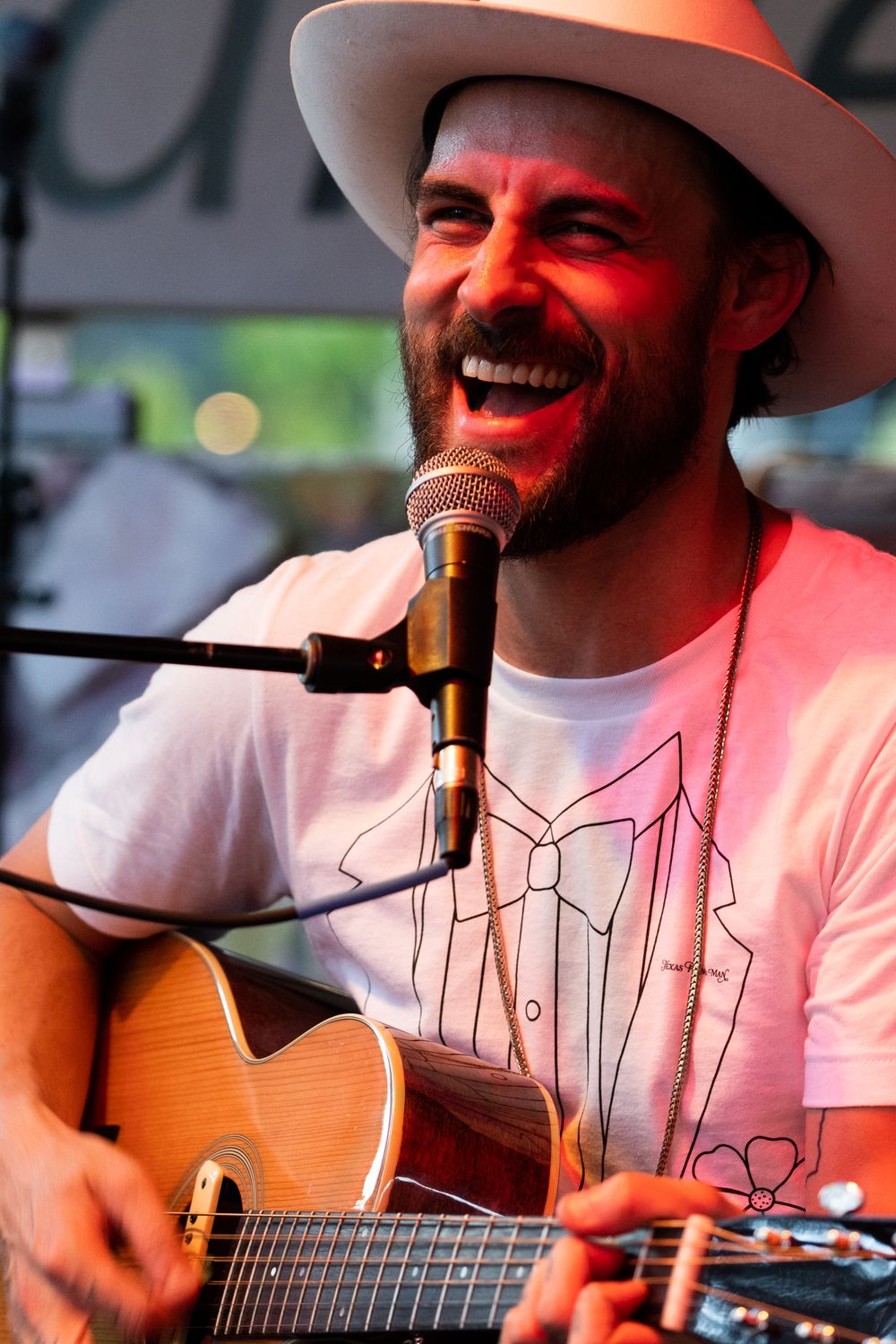 Musician smiling while singing and playing guitar