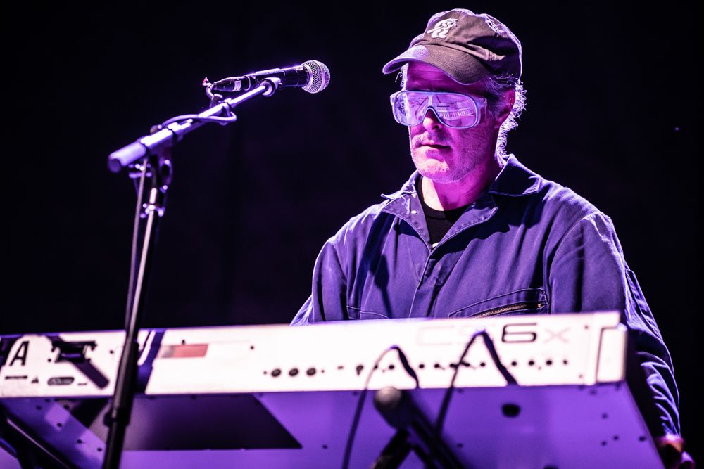 Image with a purple hue of keyboardist playing on stage