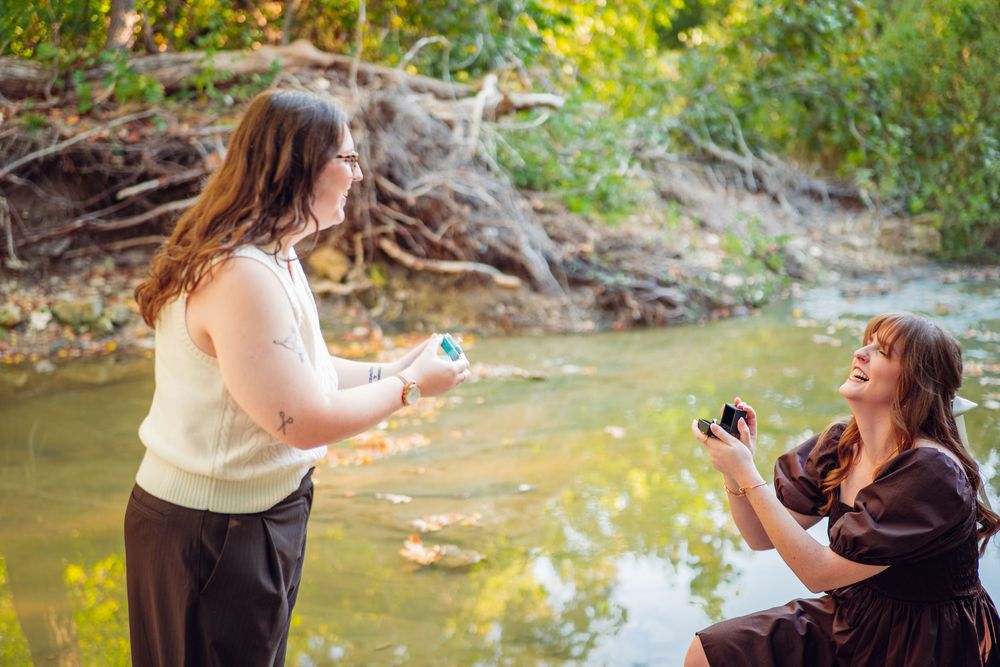 Two people share a special moment by a creek while holding small objects.