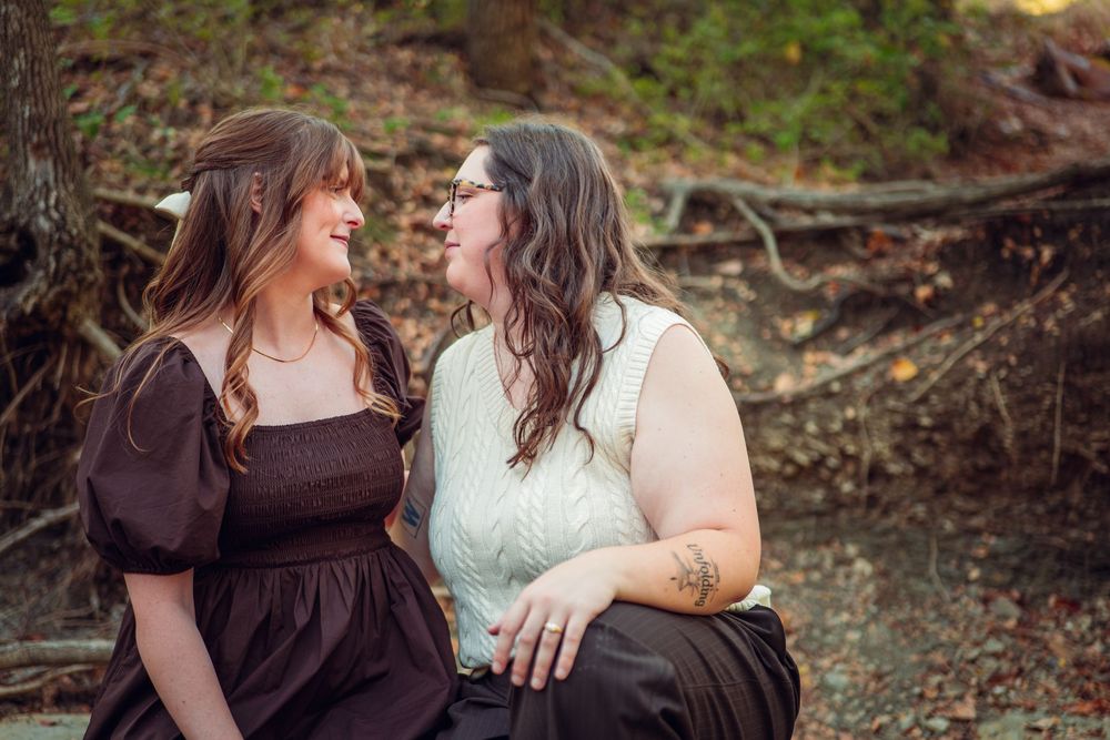 Two people share an intimate conversation while sitting outdoors in natural lighting.
