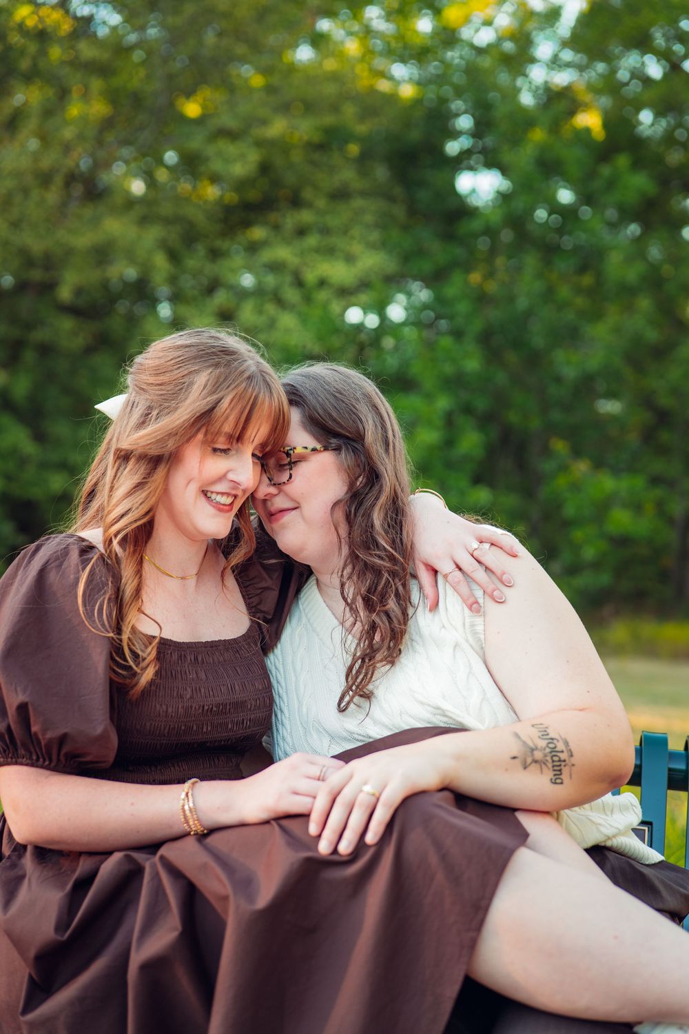 Two people share a close moment while sitting together outdoors in summer.