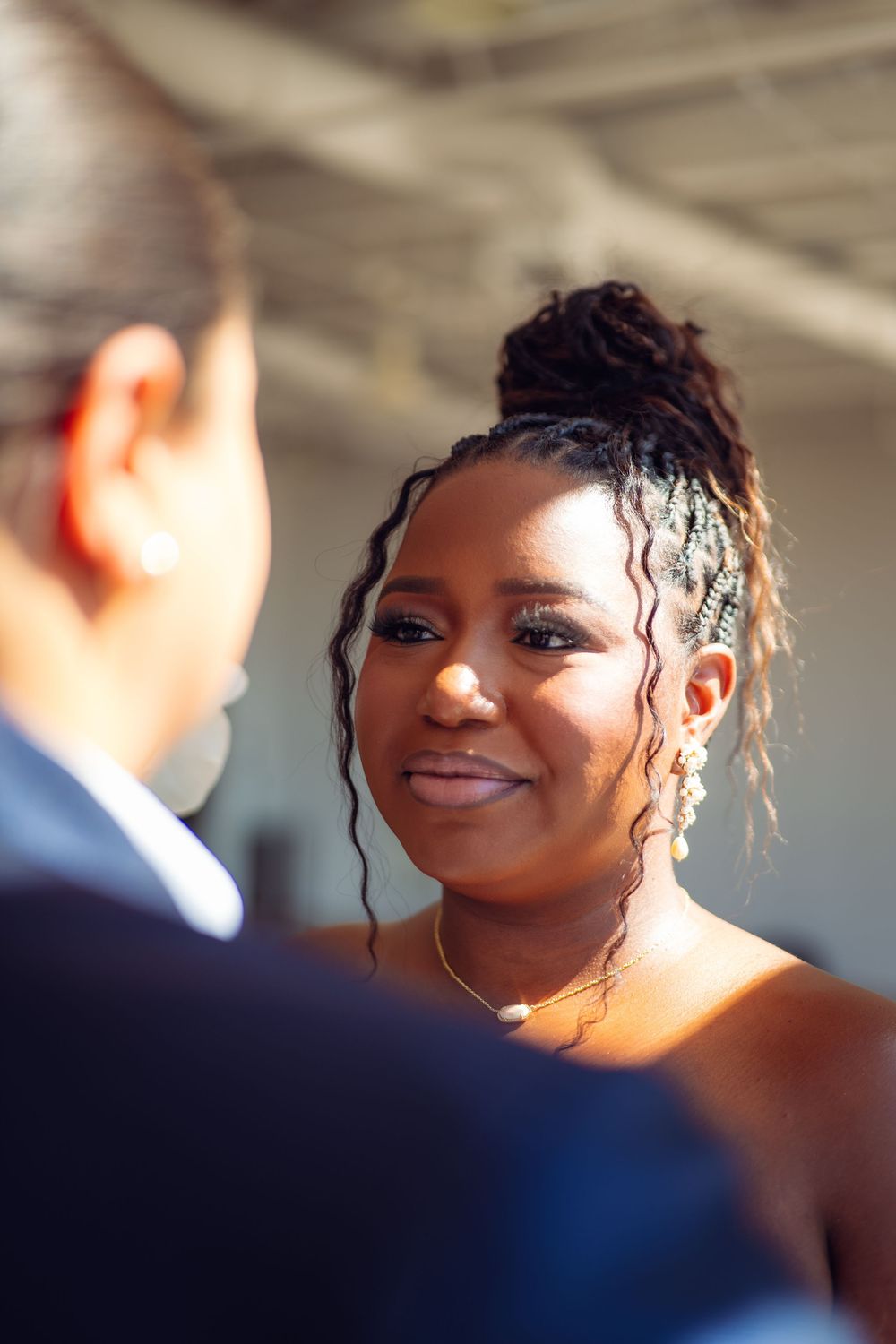 A romantic first dance moment between newlyweds in a sunlit indoor venue with exposed brick walls.