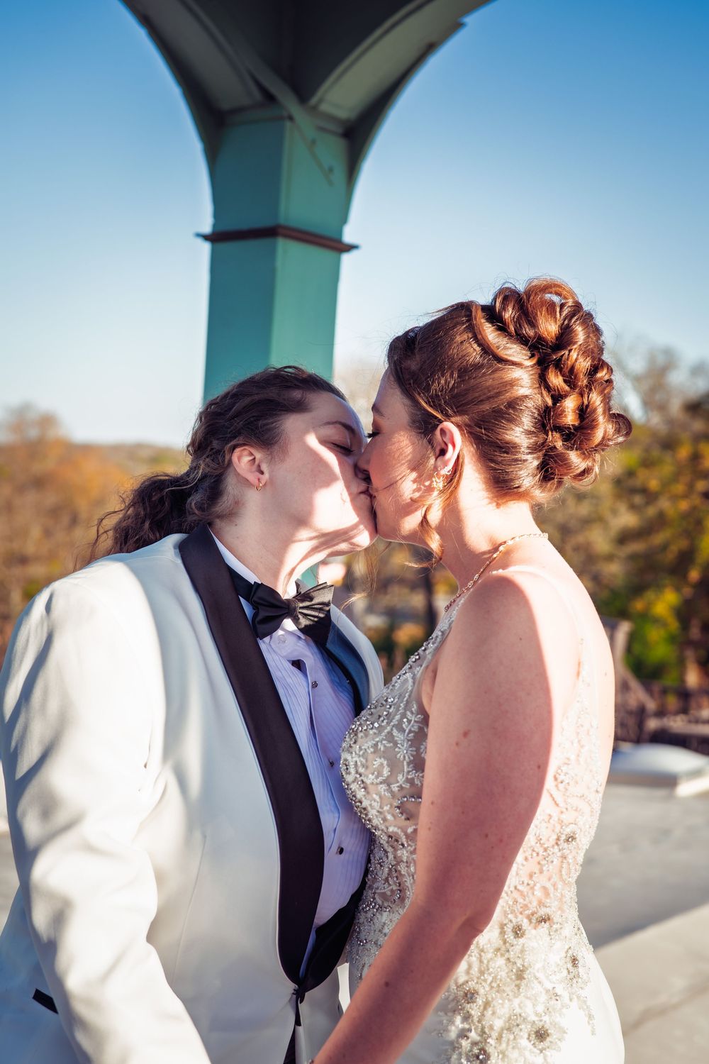 A tender wedding moment captured under a turquoise architectural detail.