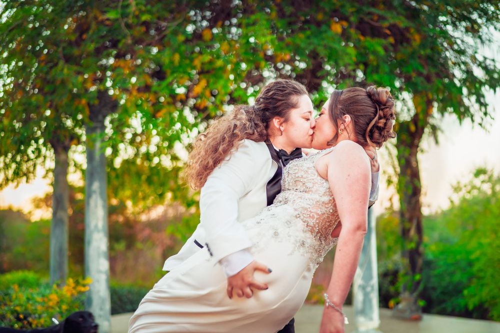 A romantic wedding portrait taken in a lush garden setting during golden hour.