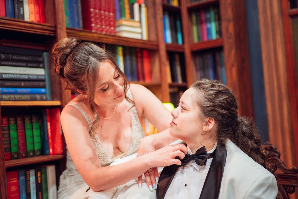 A candid moment between newlyweds in a library setting surrounded by books.