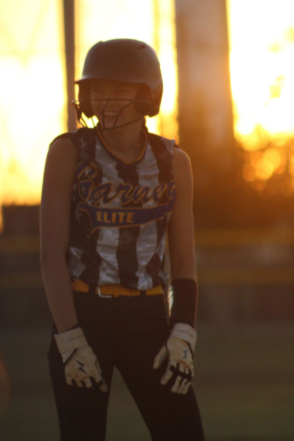 Softball player practicing at dusk with golden sunset lighting.