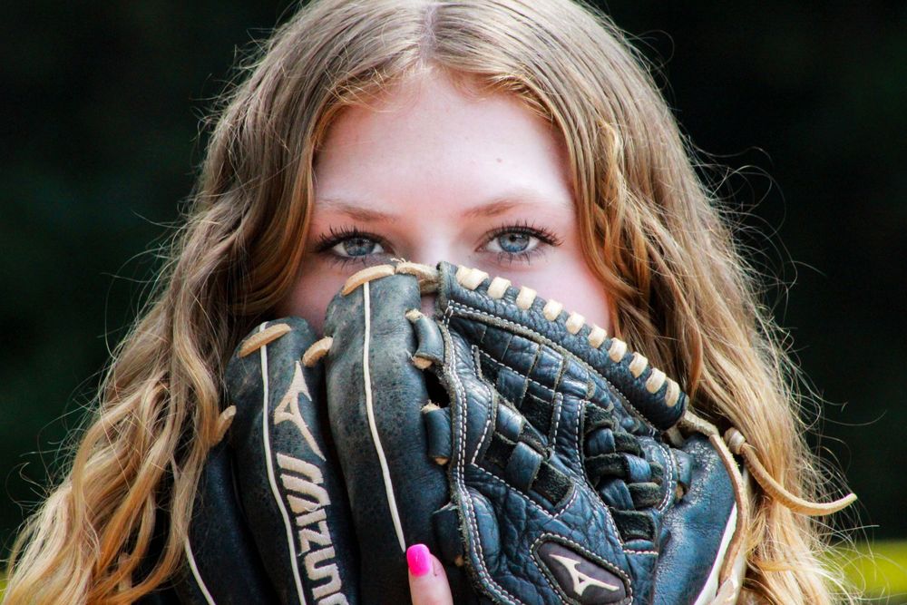 Close-up view of a leather baseball glove with blonde hair visible in background.
