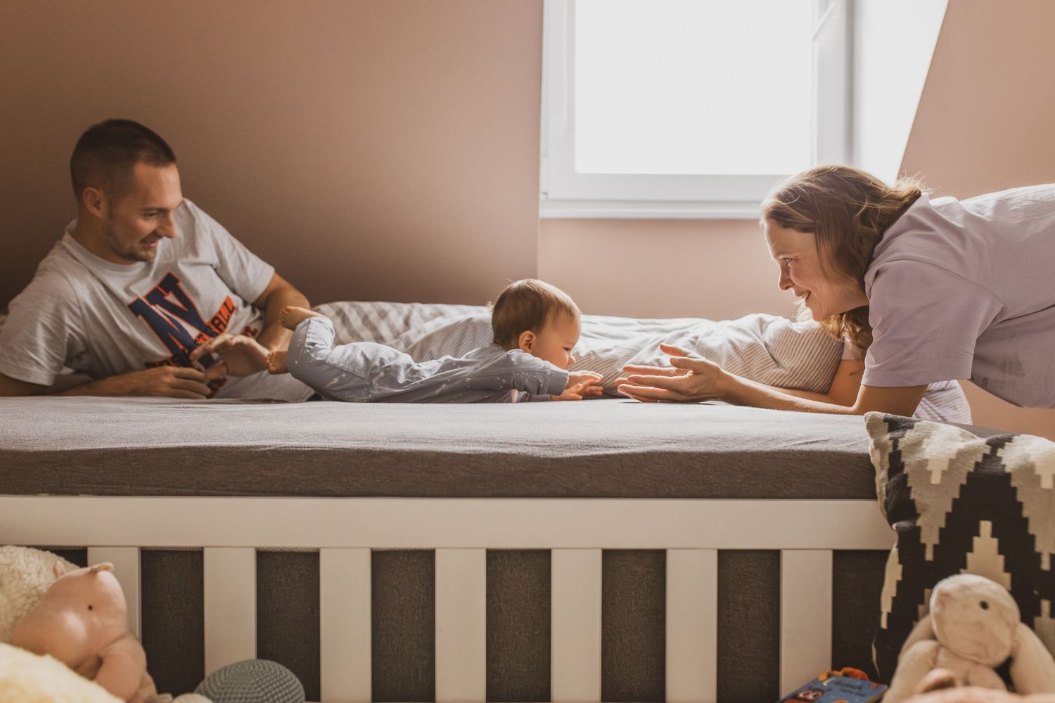 Foto von einem Papa mit einem Kleinkind auf dem Schoß, die im Kinderzimmer auf dem Boden sitzen und ein Buch anschauen.
