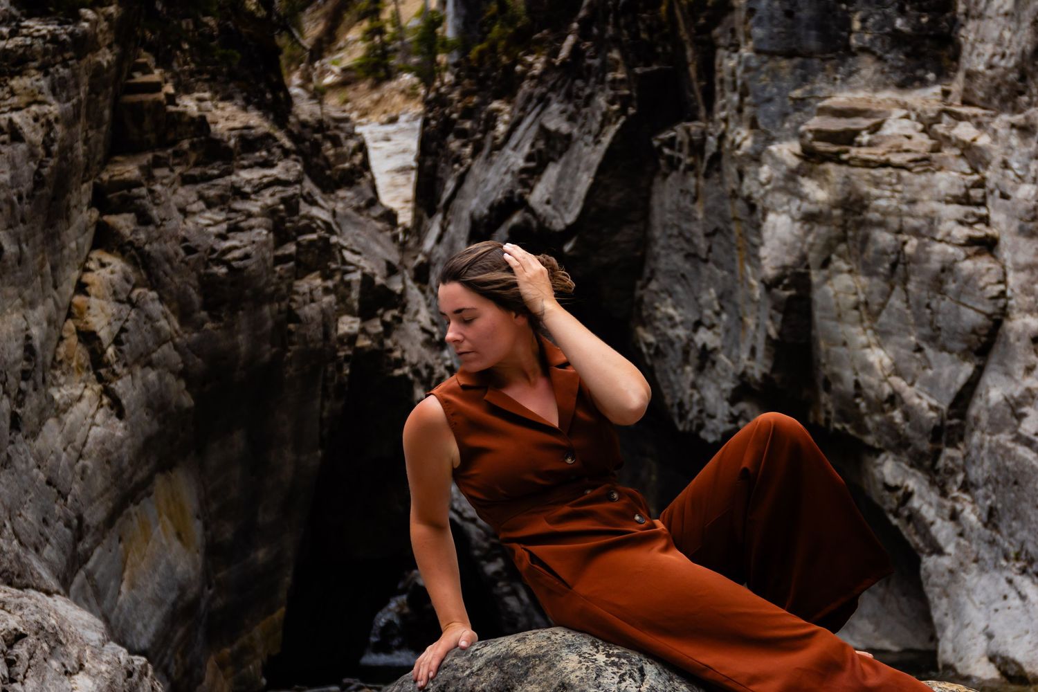 A contemplative moment captured on rocky terrain wearing a rust-colored outfit.