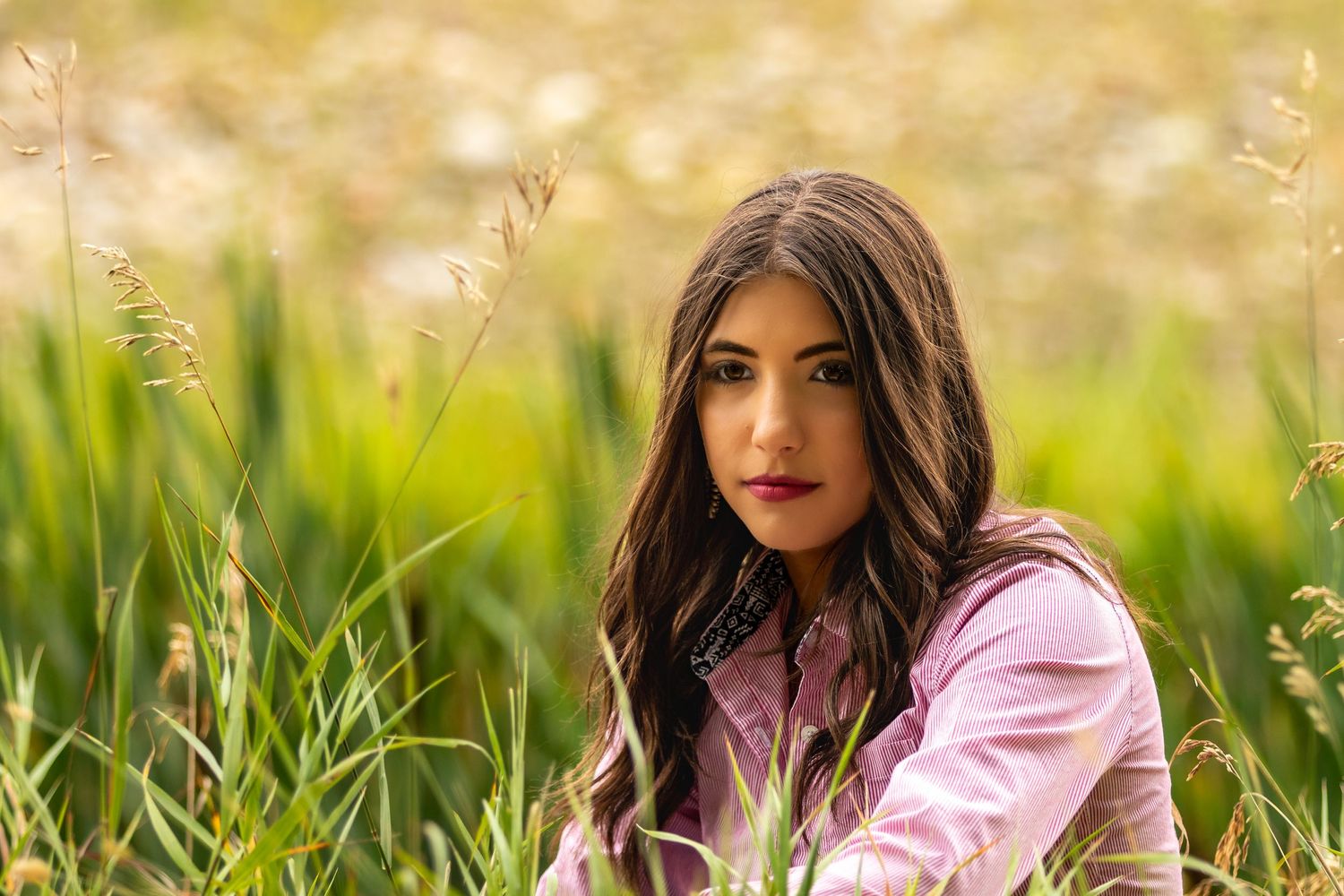 A portrait in tall grass with soft bokeh lighting and pink tones.