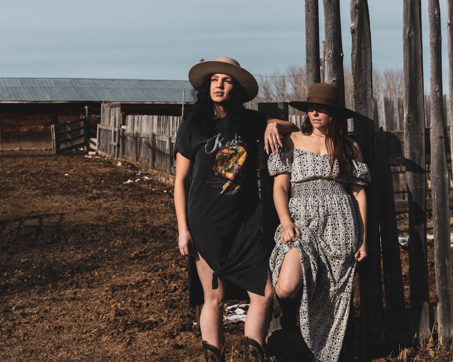 Two people in casual outfits walking together along a rustic fence line at dusk.
