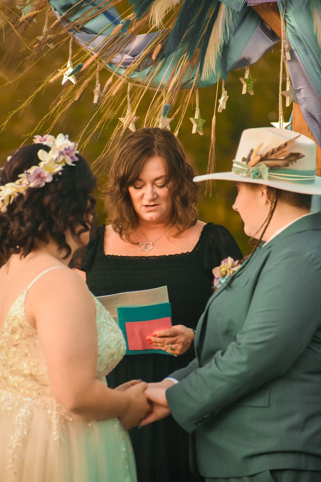 An intimate wedding ceremony under decorative hanging stars with three people standing together.