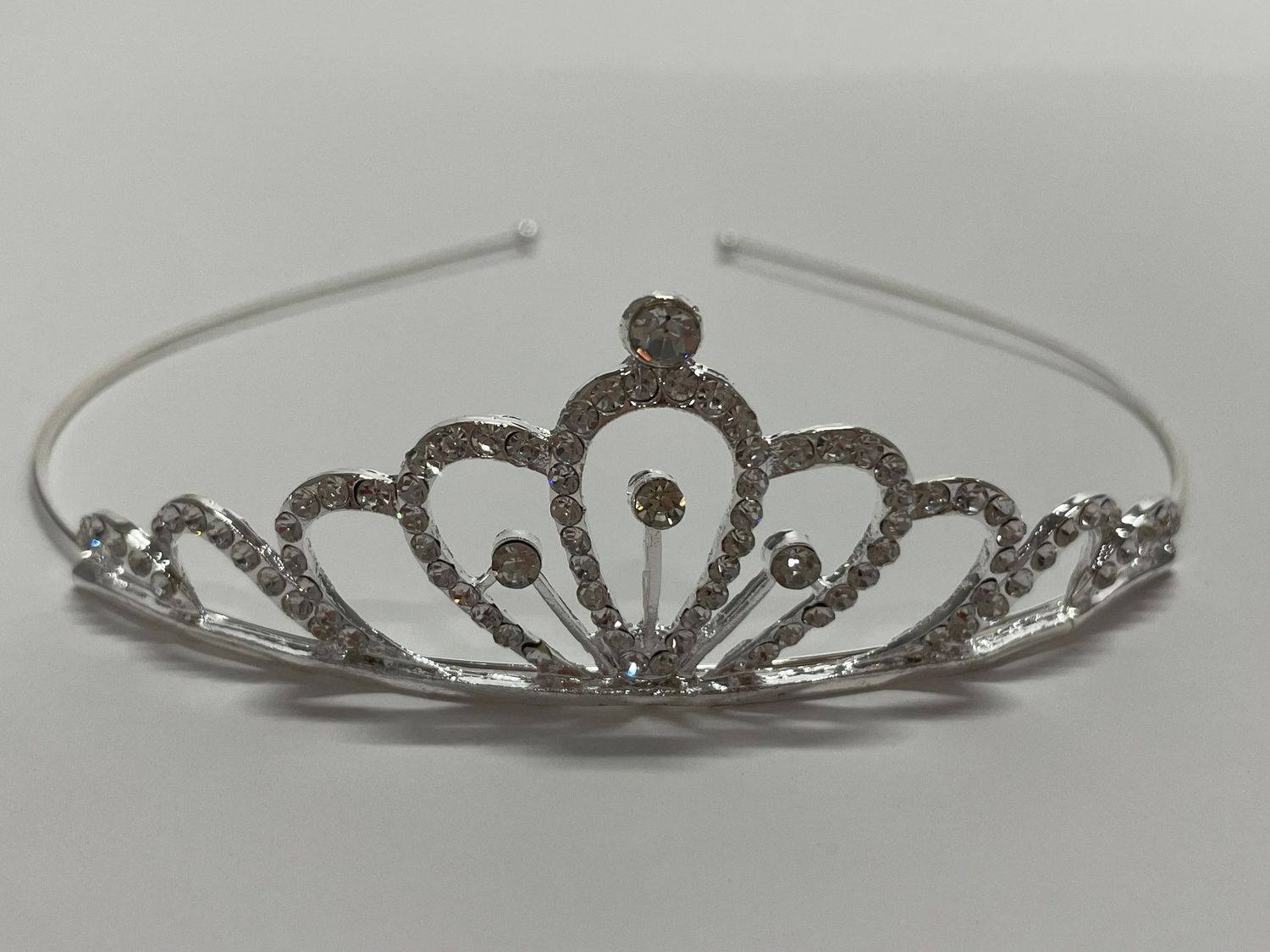 Crystal-studded silver tiara featuring a classic princess crown design with ornate details.