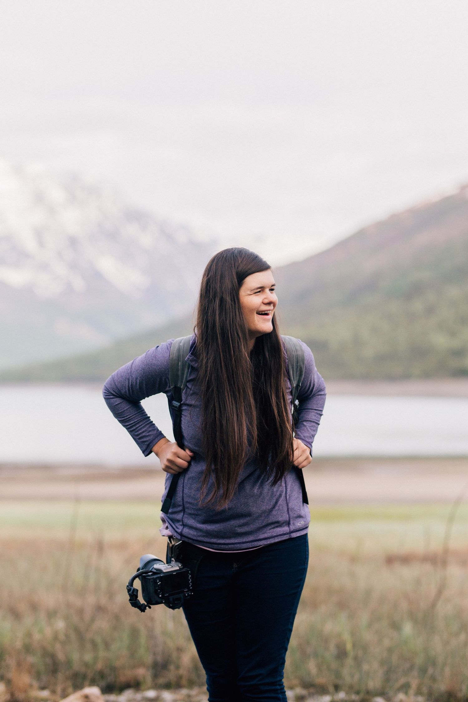 Photographer with camera in purple shirt enjoying mountain landscape view.