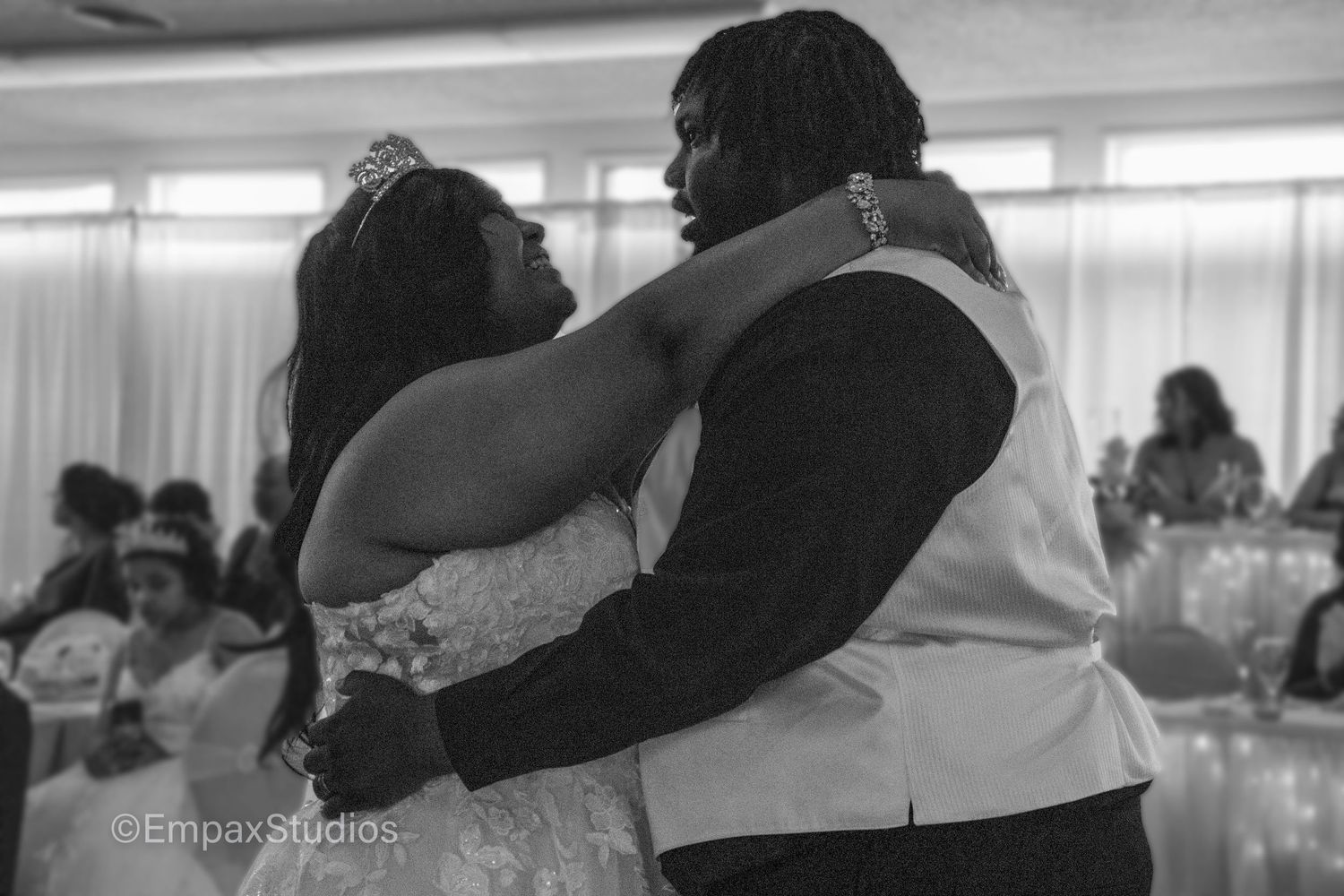 A black-and-white photo of a bride and groom sharing their first dance at the wedding reception, capturing a tender moment