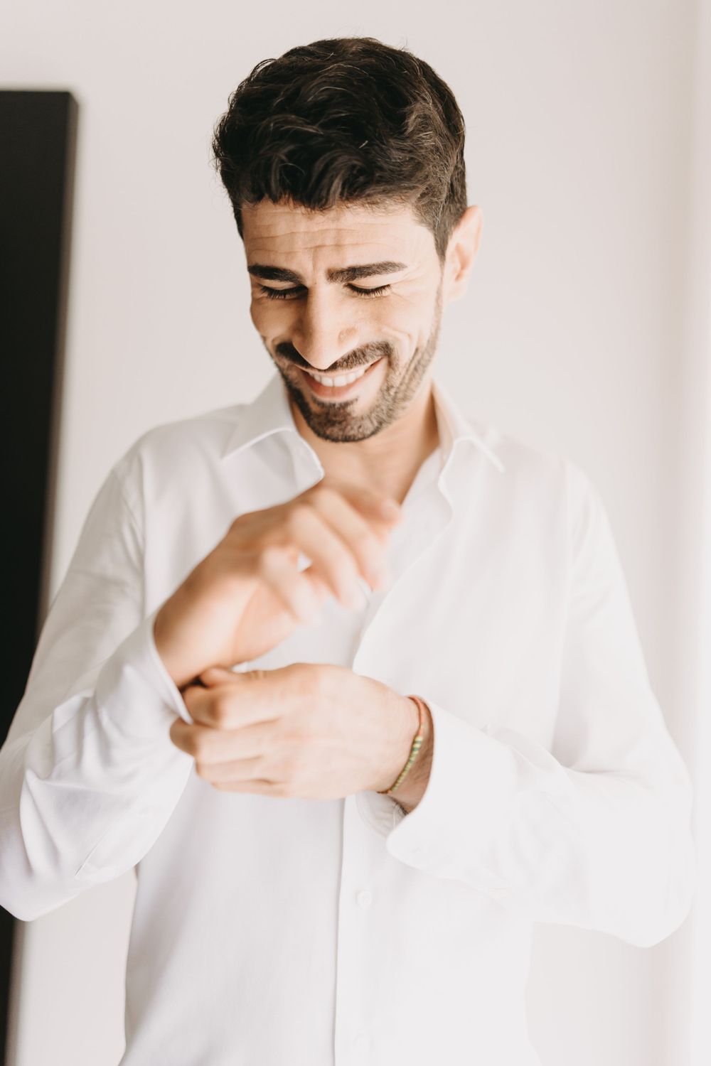 Candid moment of joy captured in white shirt during wedding preparation.