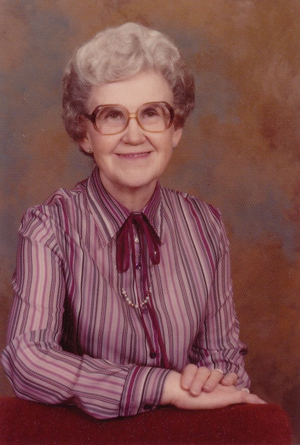 Maxine Kent, poses in vertical striped purple blouse with "Granny style" short gray hair, glasses and smile.