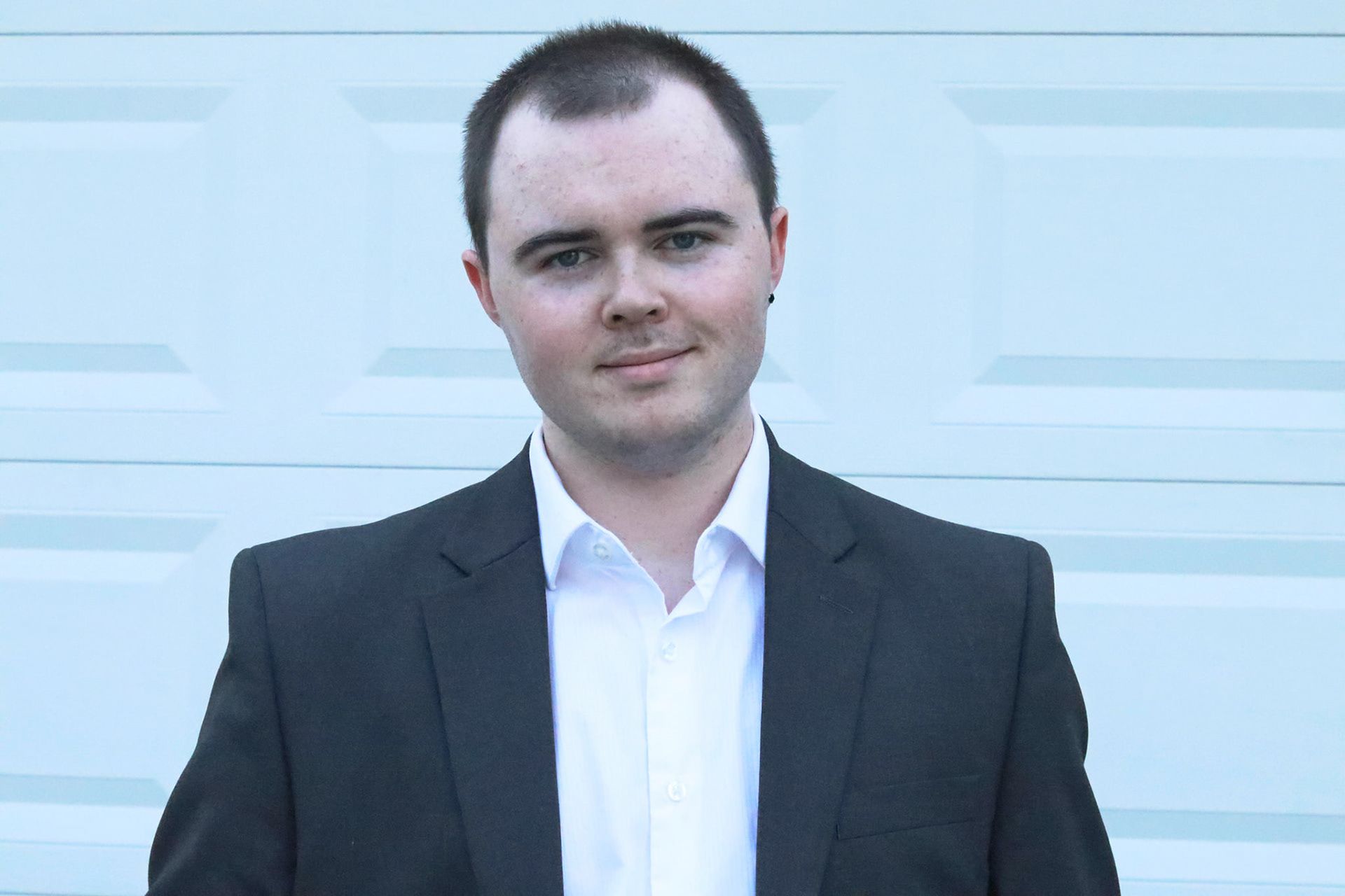 Professional headshots of person in dark suit against light background.