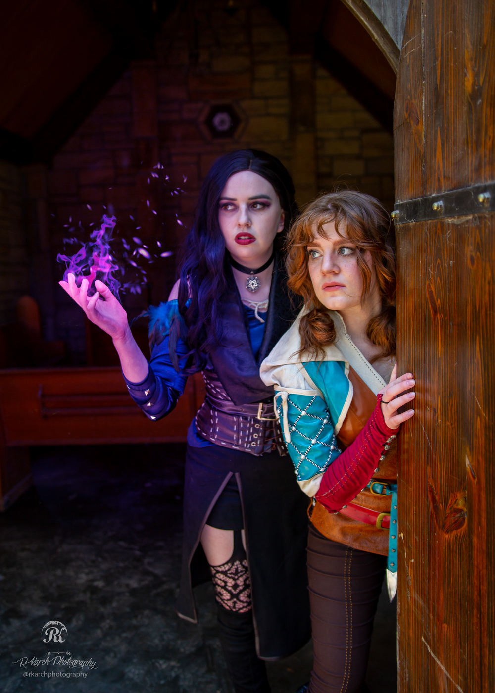 Fantasy cosplay duo in steampunk and medieval inspired costumes pose in atmospheric lighting.