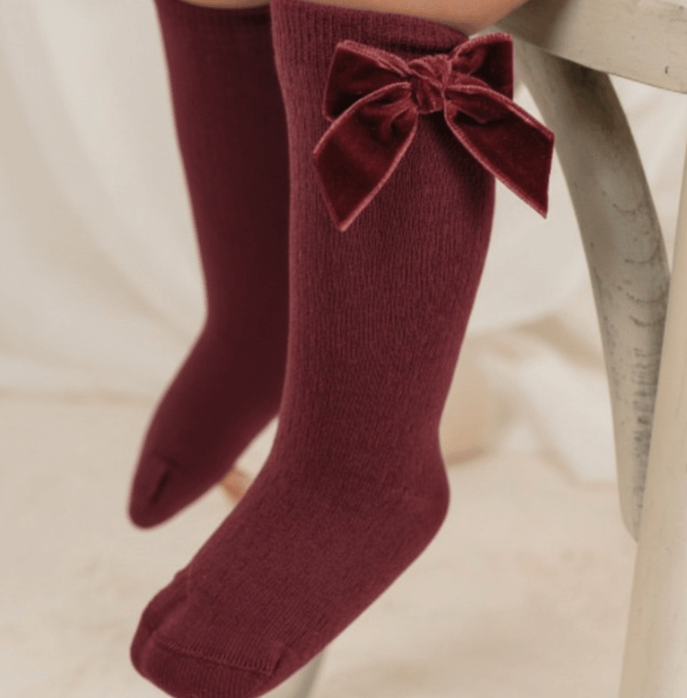 Burgundy knee-high socks with velvet bow detail for girls.